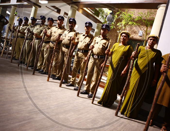 Police Man And Woman Holding Wooden Sticks In Hand in a Police Station