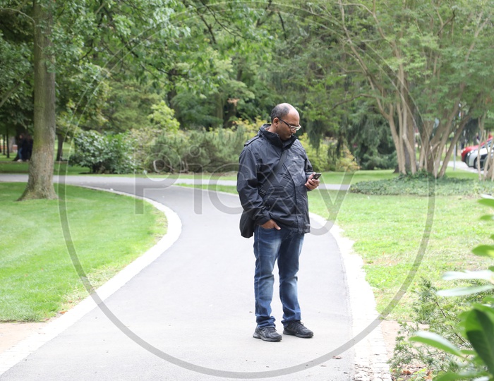 An Indian Man Using Mobile Phone In a Park