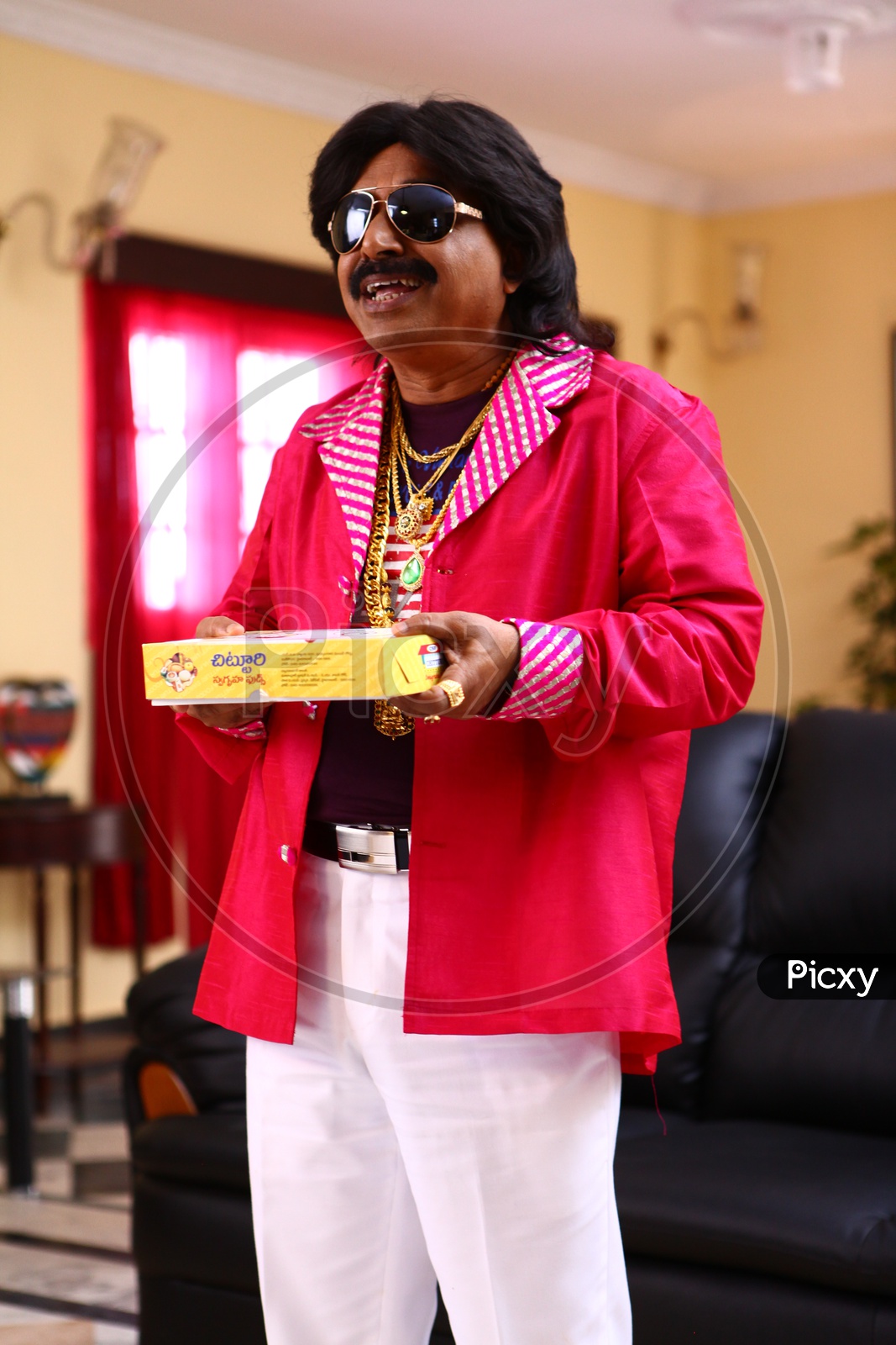 A Man Wearing Gold ornaments And Carrying Sweets Box