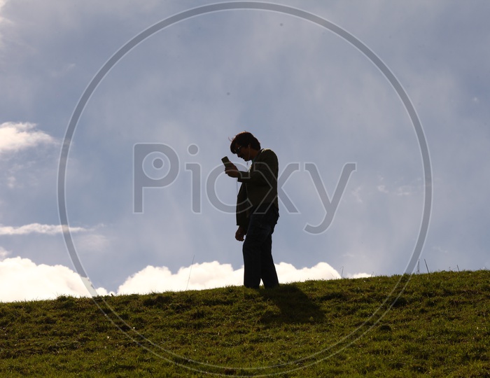 Silhouette Of a Man Using Mobile Over a Bright Sky