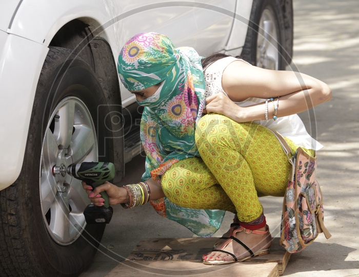 Young Girl Unscrewing The Car Wheel Nuts Or Bolts