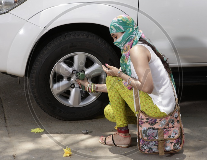 Young Girl Unscrewing The Car Wheel Nuts Or Bolts