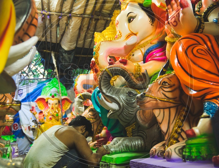 A person giving final touches to the ganesha idol