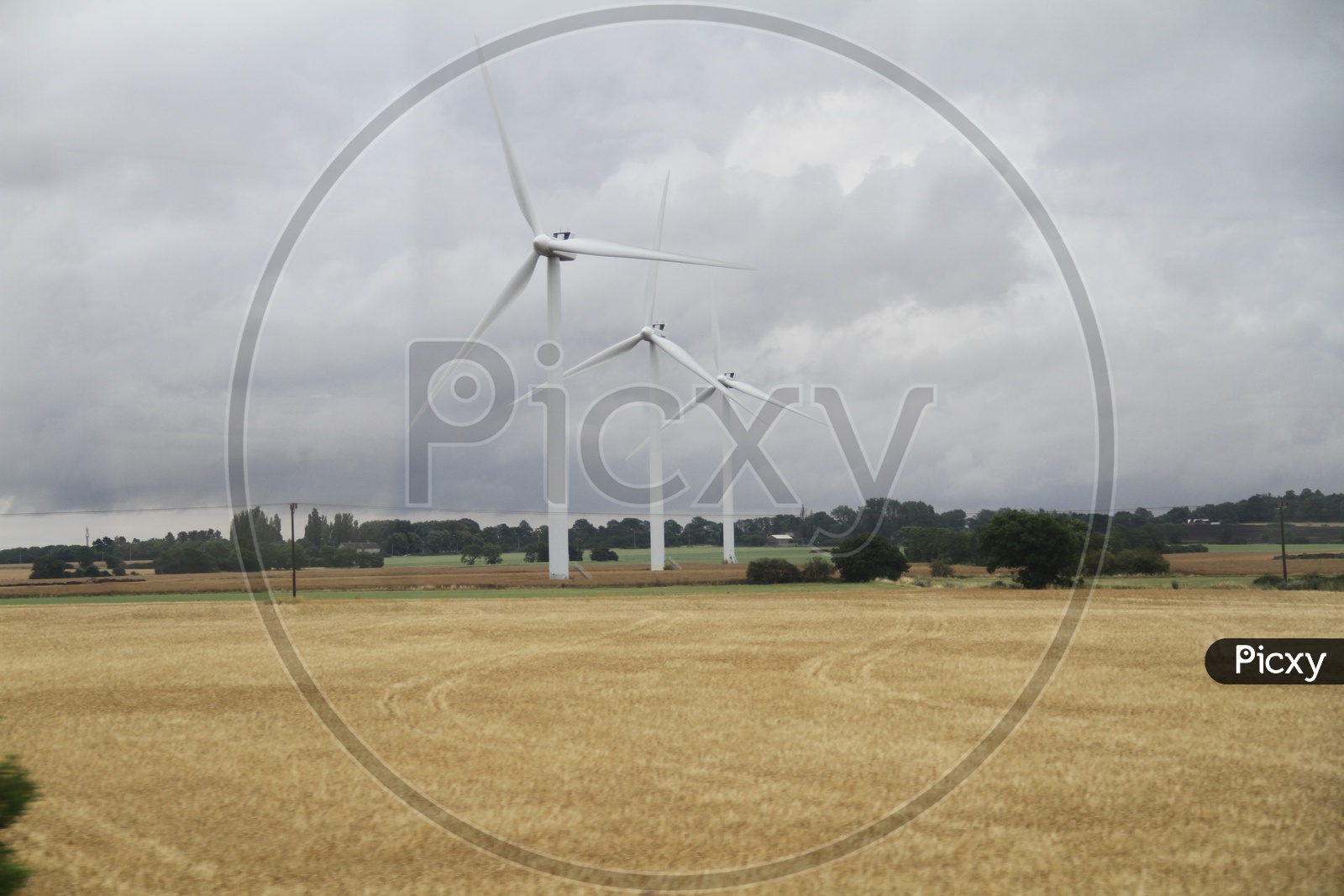 Wind Turbines in Field with Clouds in Sky Background