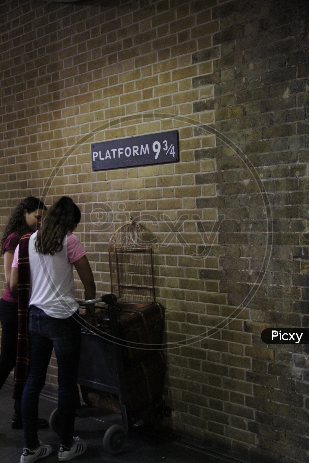 Young Women at Platform 9 3/4 Sign from Harry Potter movie in King's Cross Station