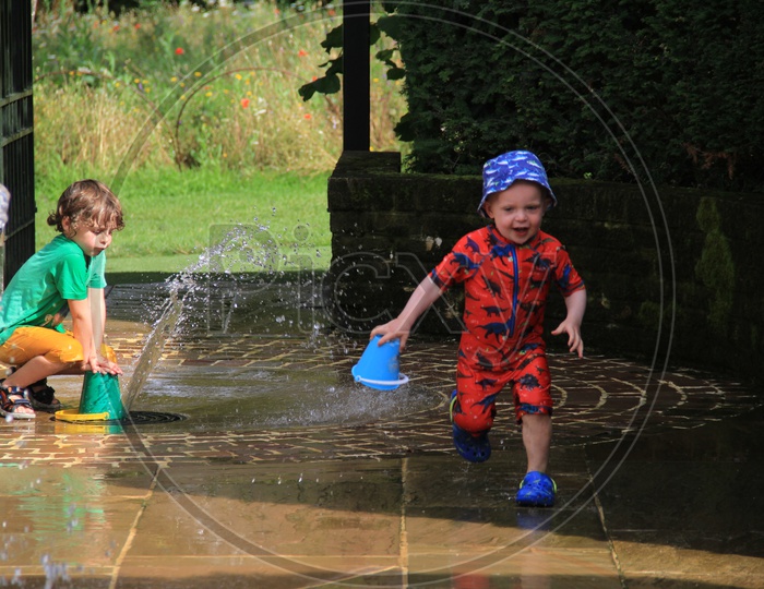 Cute Little Kids Playing with Water in a Park