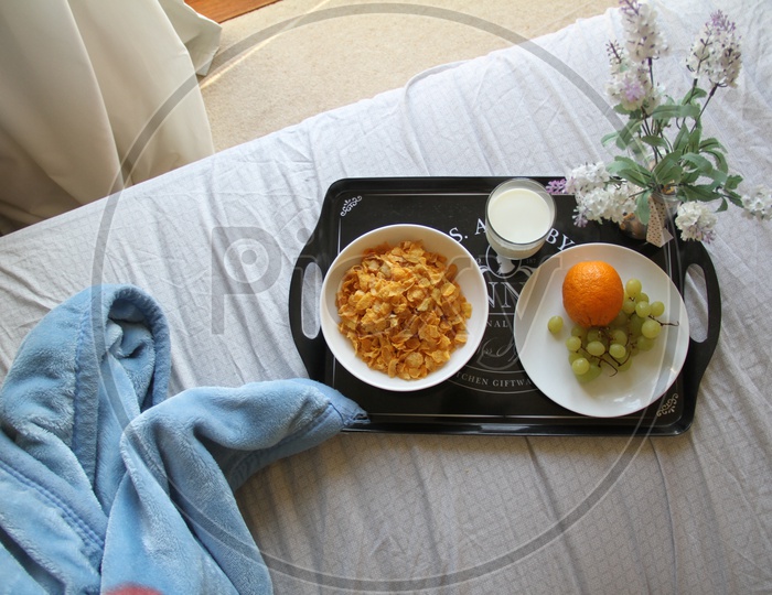Flat lay of Morning Breakfast Corn Flakes and Fruits in a Plate on Bed