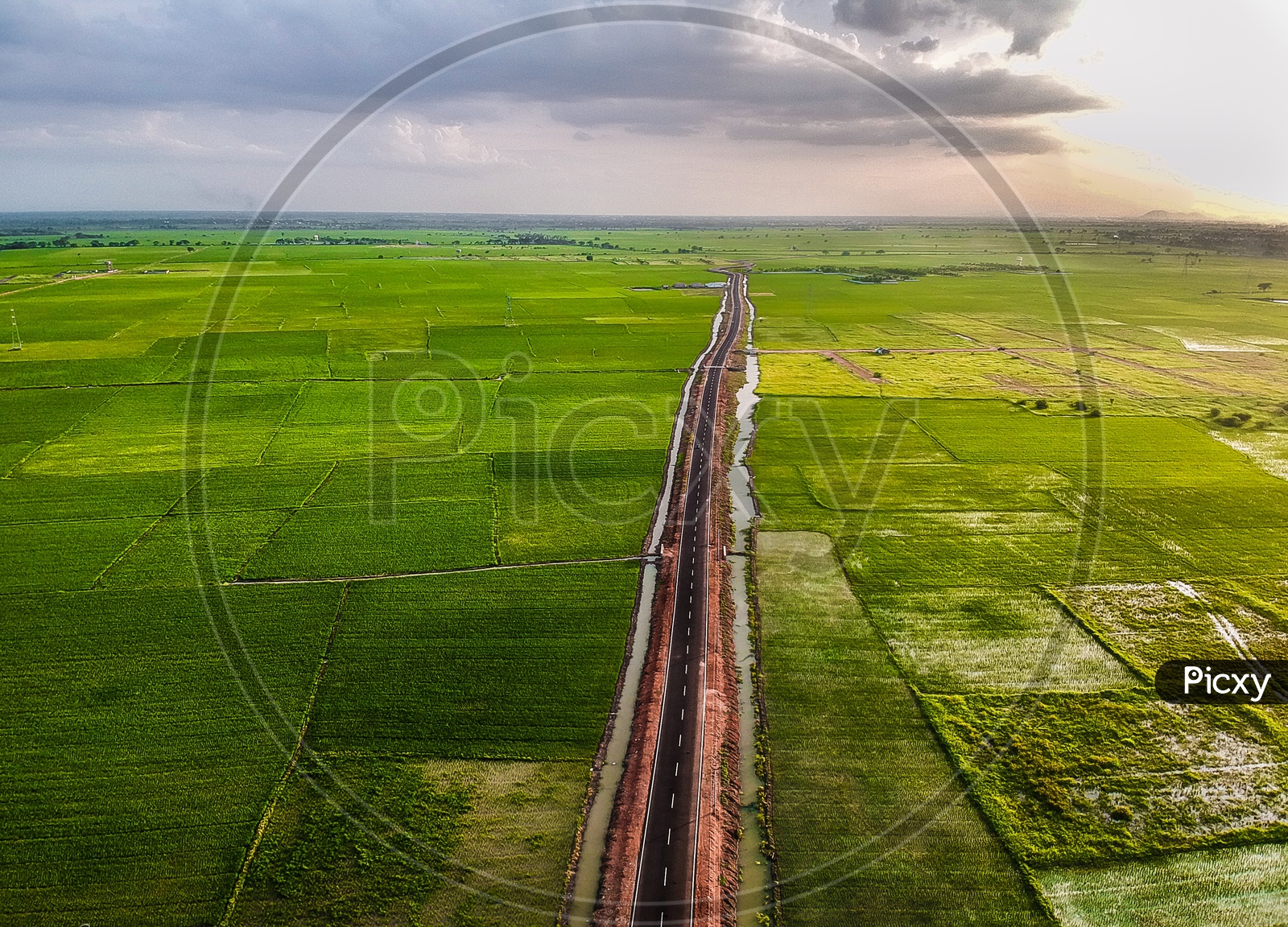 Drone shot of a road next to paddy fields 