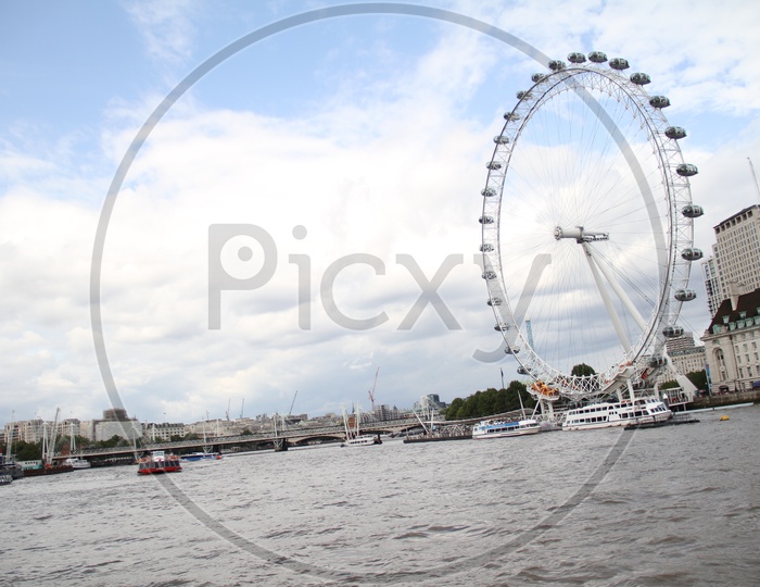 Tourist Boats and London Eye with Clouds in Sky