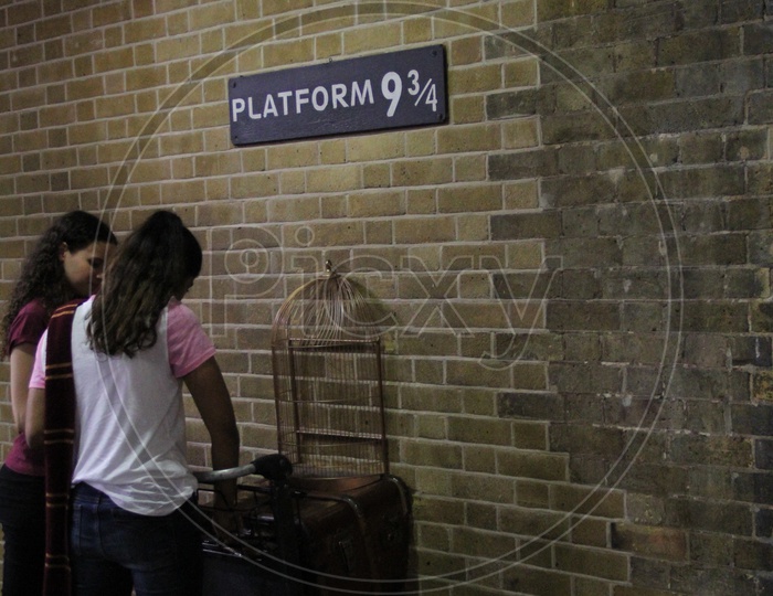 Young Women at Platform 9 3/4 Sign from Harry Potter movie in King's Cross Station