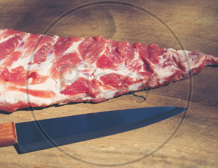Raw ribs with a rosemary and knife on chopping board