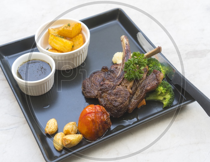 Organic Grilled Lamb Chops with Garlic and Lime in a black tray