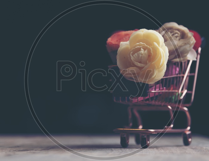 Shopping Cart With Flowers over Black Background For Valentines Day Love Concept