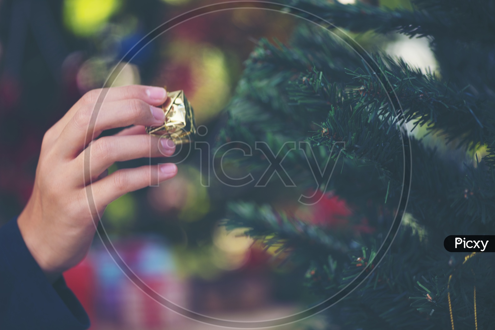 Woman Hands Decorating Christmas tree With Bells And Gifts For Christmas Festival