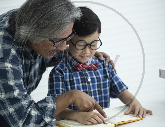 Older teacher helping a boy student to do homework, education concept