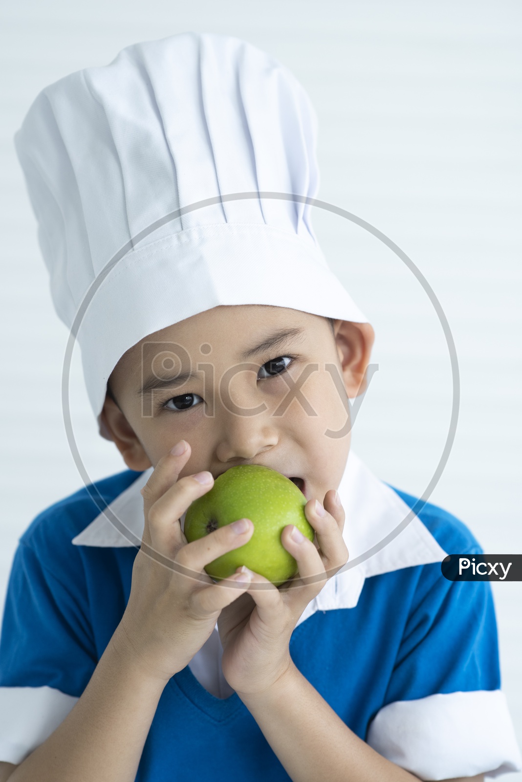 Boy as chef eating green apple