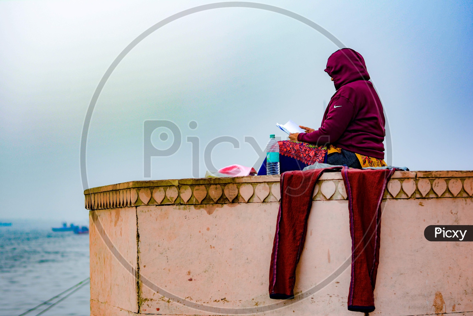 A women reading a book in calm atmosphere of ganges river