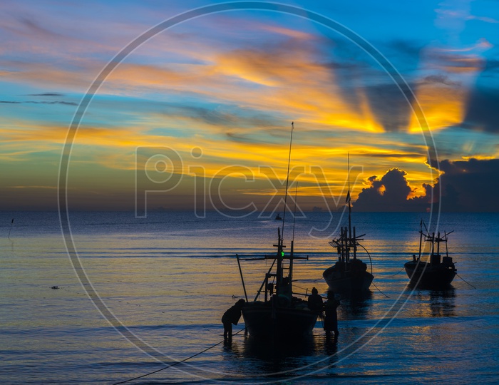 Fishing Boats In a Beach With  Fisherman Carrying Their Catch Over a Blue hour  Sunset Sky In Background
