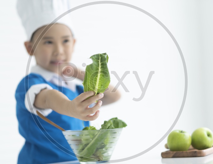 A boy as chef enjoying cooking with spinach in hand