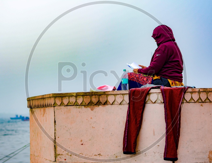 A women reading a book in calm atmosphere of ganges river