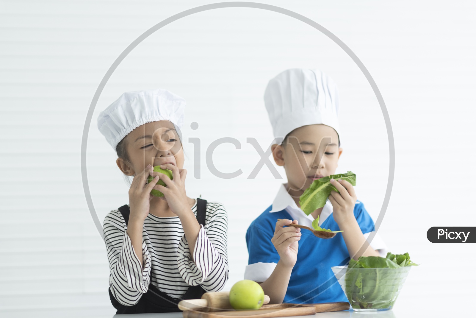 Boys as chefs enjoying cooking with vegetables  in hand
