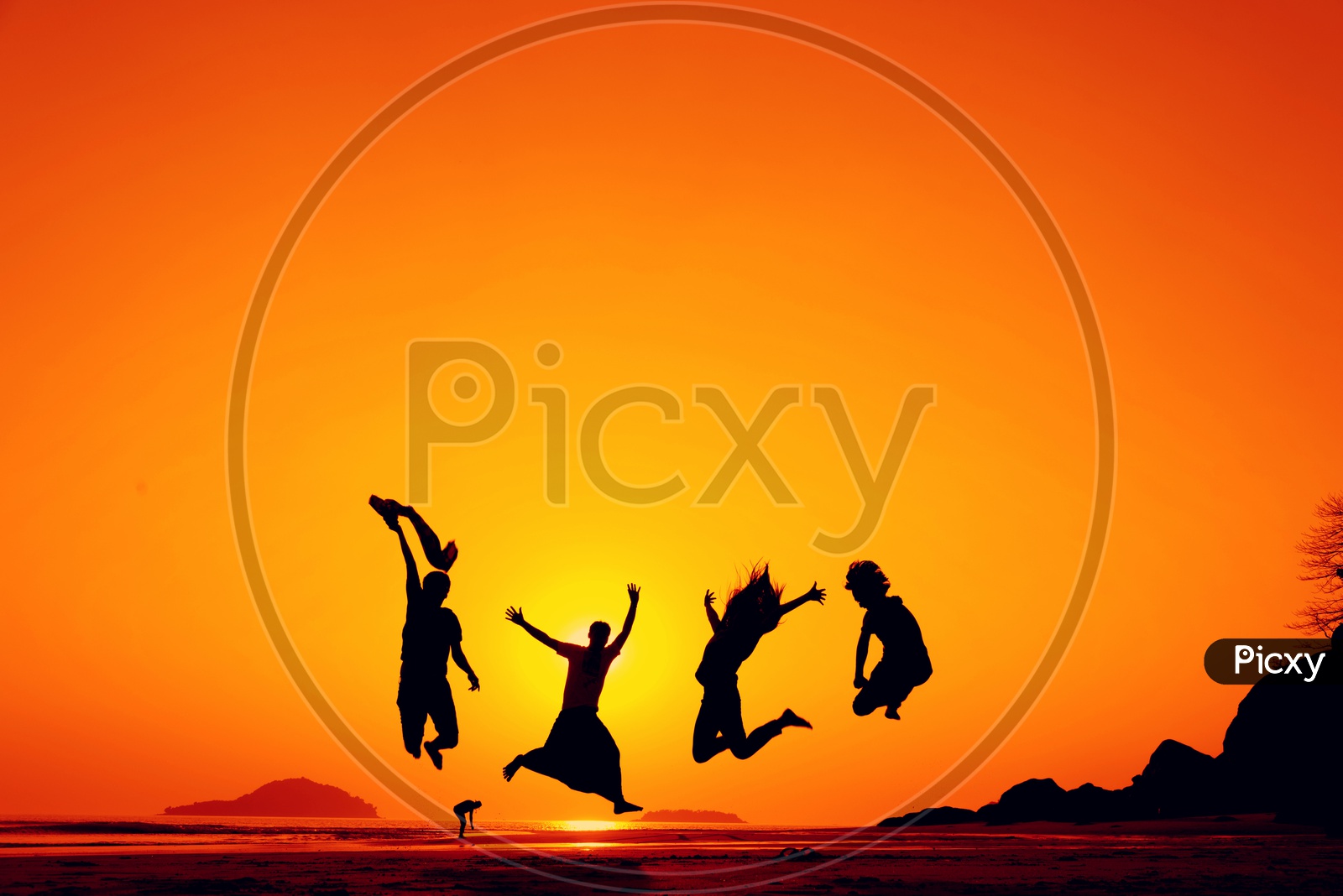Silhouette Of Young Happy People Jumping in Joy Over a Sunset Sky  at  a Beach