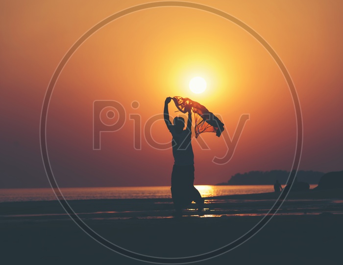 Silhouette Of Young Man  Chilling In A Beach Over Sunset
