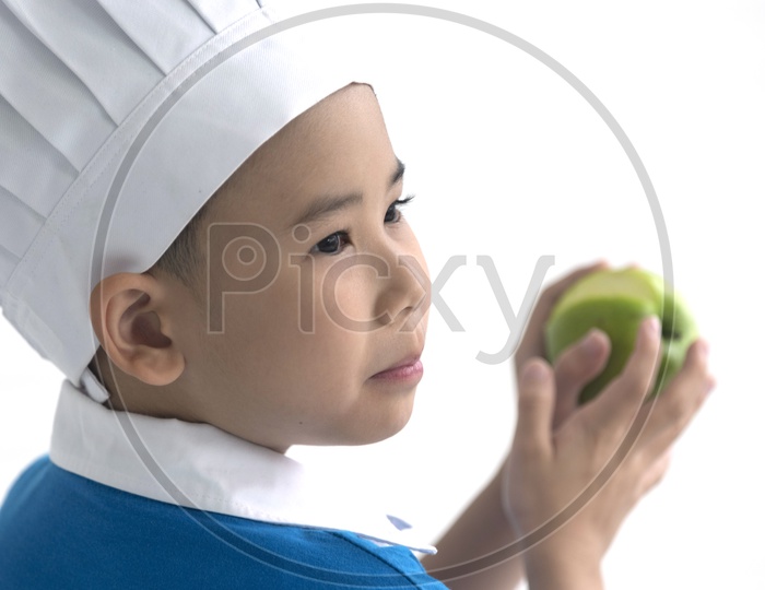 Boy as chef enjoying cooking with apple in hand