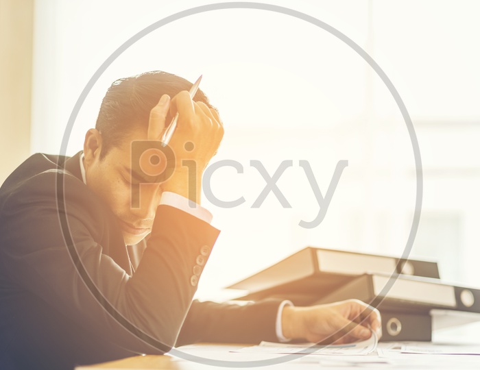 Stressed Asian businessman holding a pen