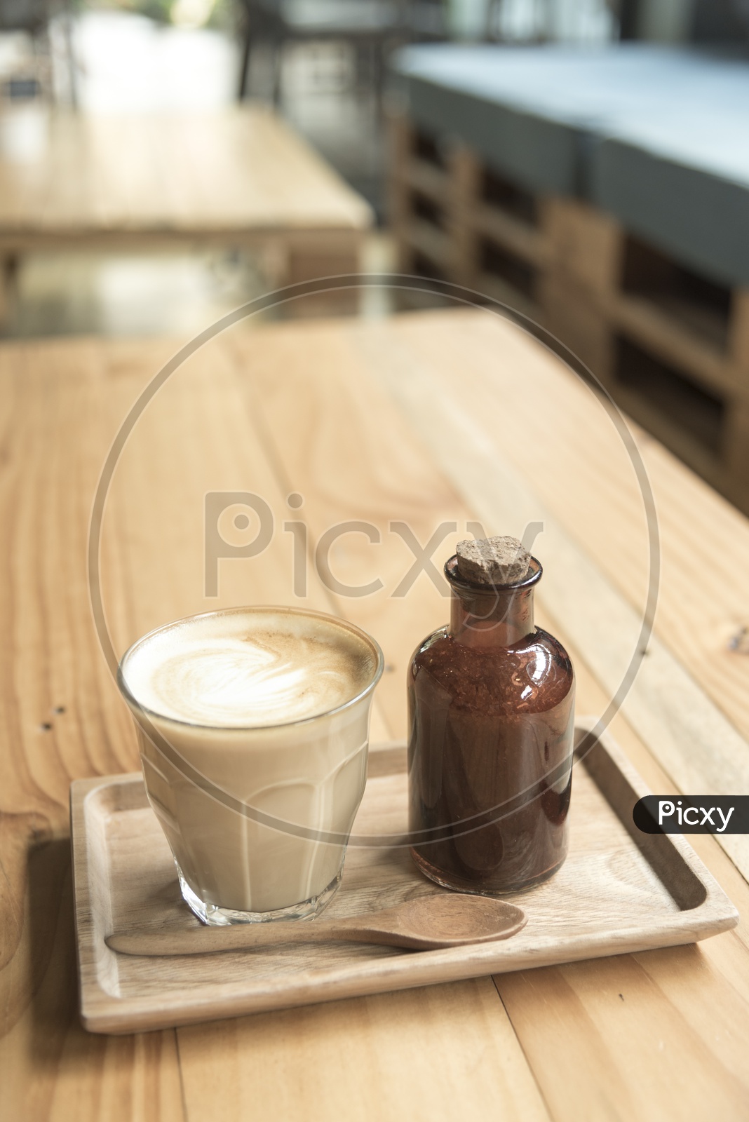 Coffee Latte Art On a Coffee With Sugar Syrup Bottle On Cafe Wooden table Background