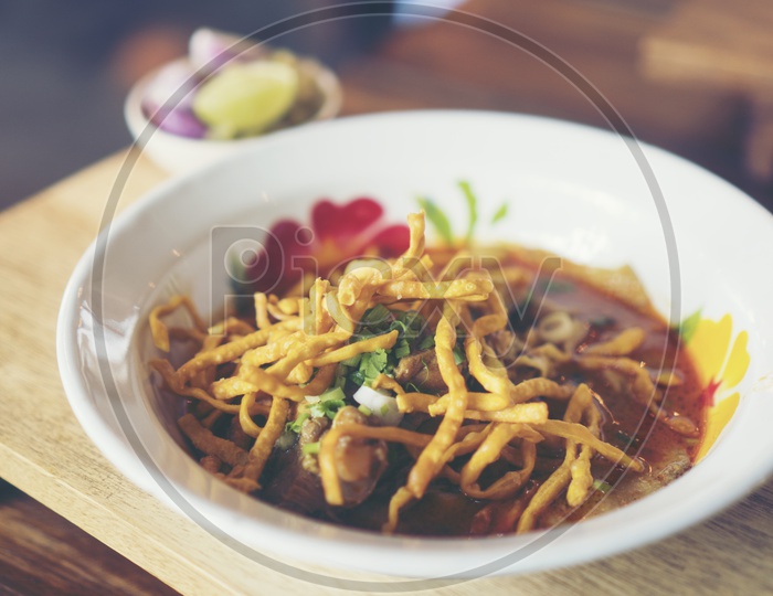 Close up of a beautiful set of Khao Soi, local northern food of Thailand. Khao soi is chicken with curry with crispy noodle on top.