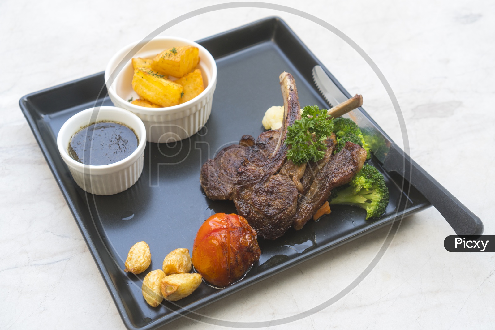 Organic Grilled Lamb Chops with Garlic and Lime in a black tray
