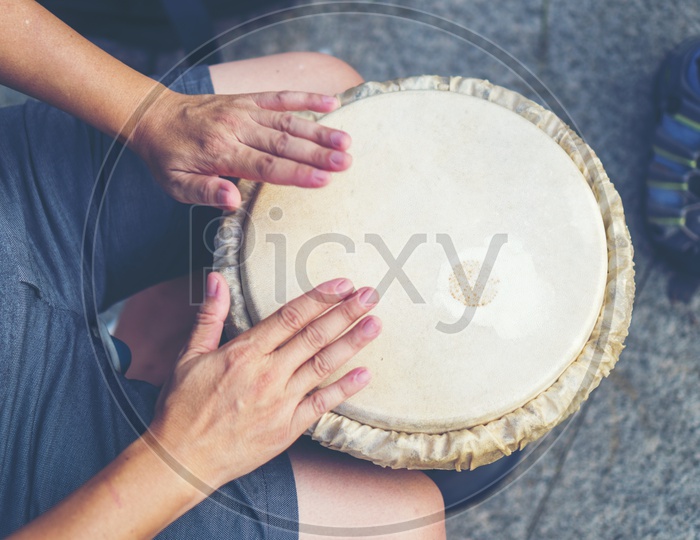 Top veiw of a man's hands playing music at djembe drums, vintage filter image