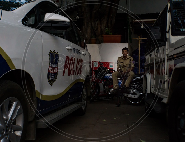 View of a policeman sitting on a bike, besides police cars