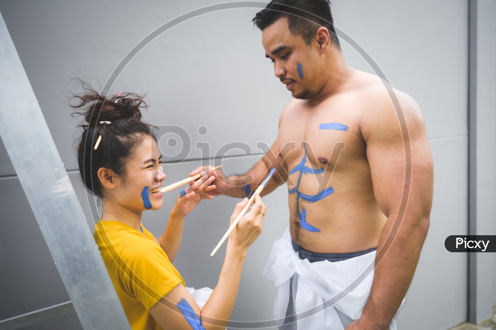 Affectionate Lovely Couple Celebrating love by Painting Their Bodies With Paint With brushes And Enjoying  in a House