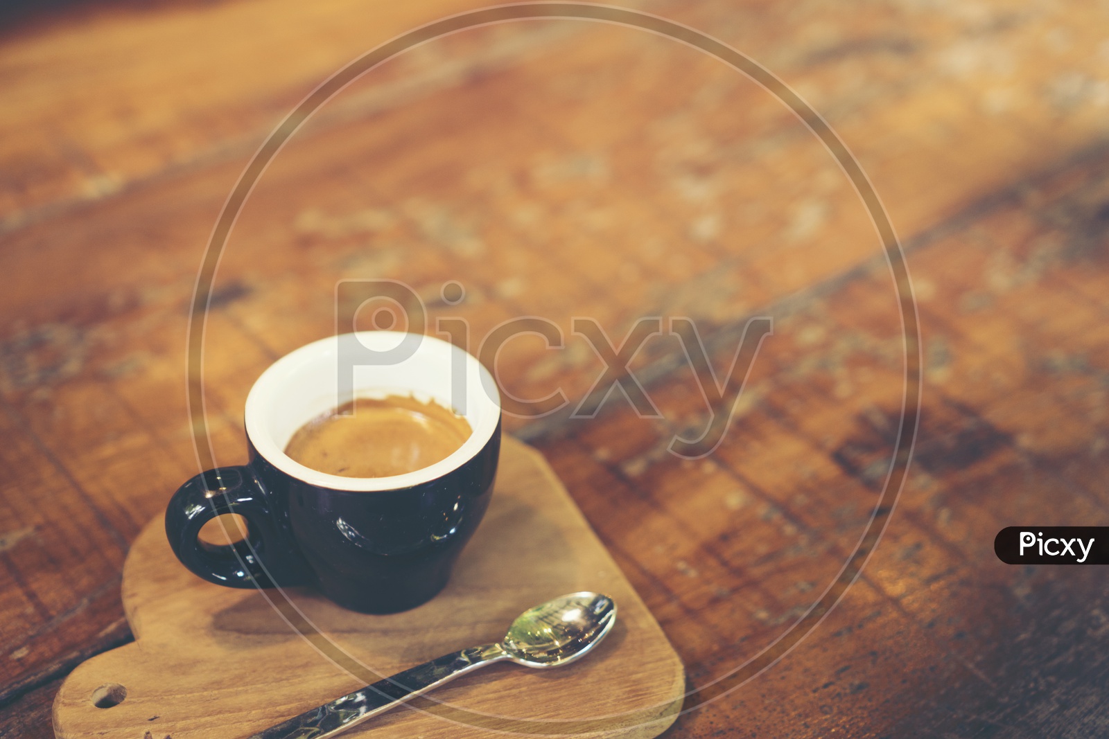 Espresso shot coffee in a black cup on a wooden tray