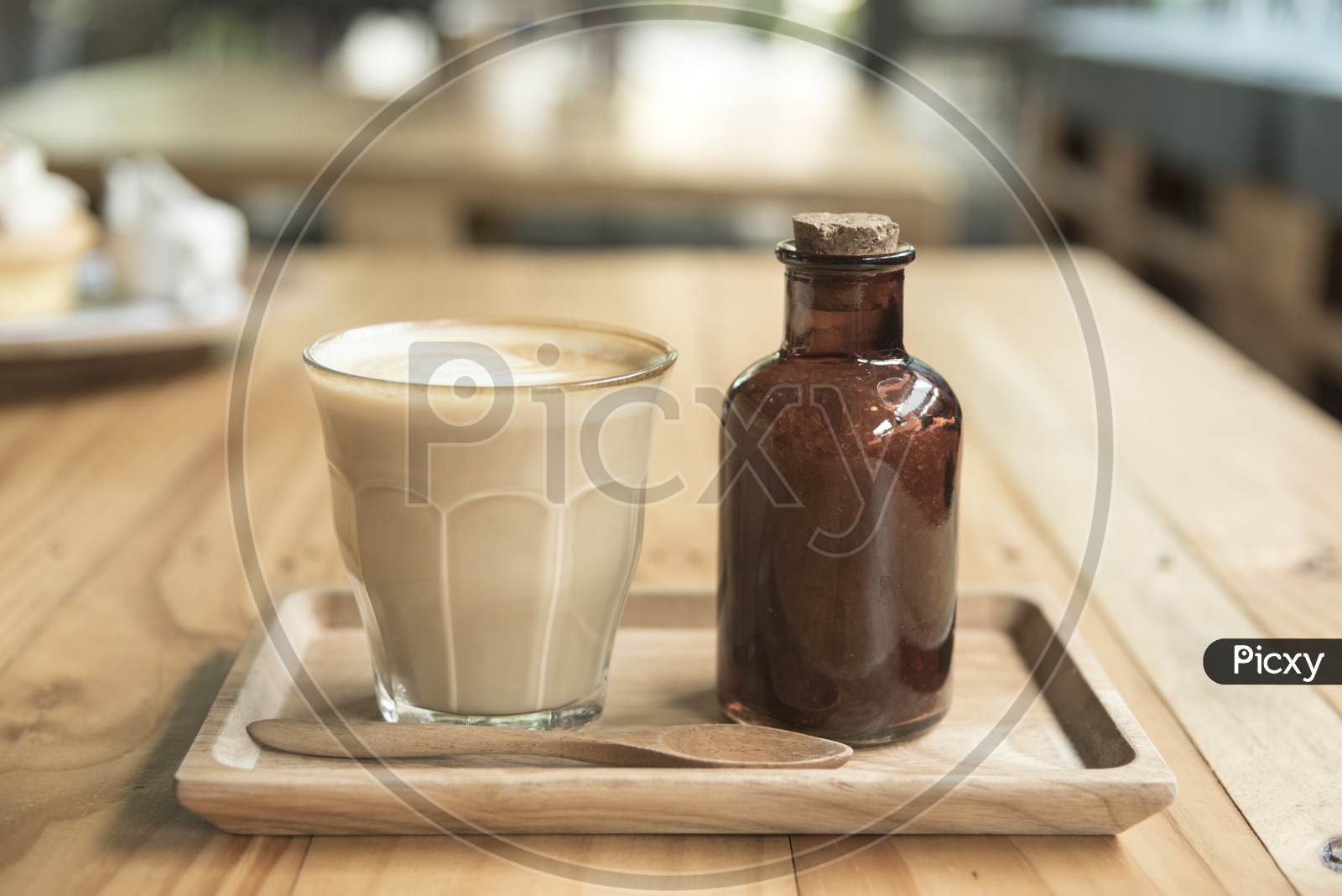 Coffee Latte Art On a Coffee With Sugar Syrup Bottle On Cafe Wooden table Background