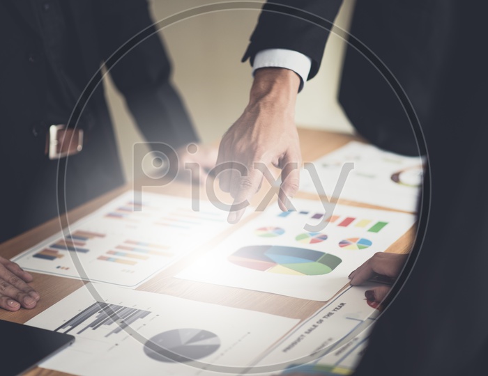Businessman Verifying Statistics and Charts  Of Business Growth Over a office desk Backdrop