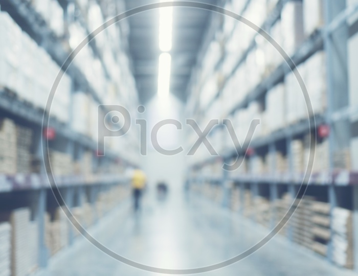 Blurred image of shelf in modern distribution warehouse or storehouse. Defocused background of industrial warehouse interior aisle