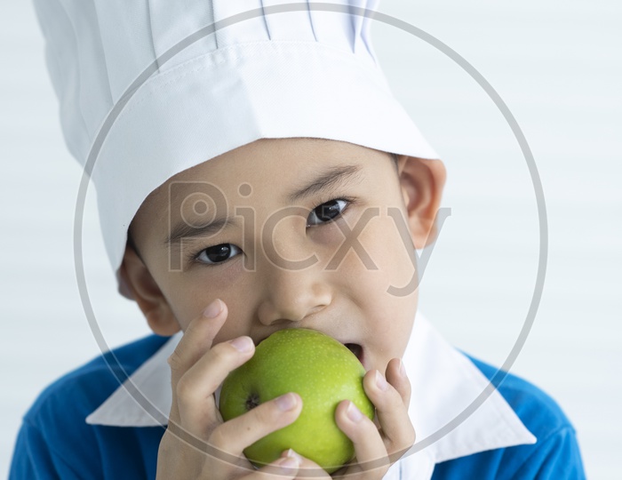 Boy as chef eating green apple