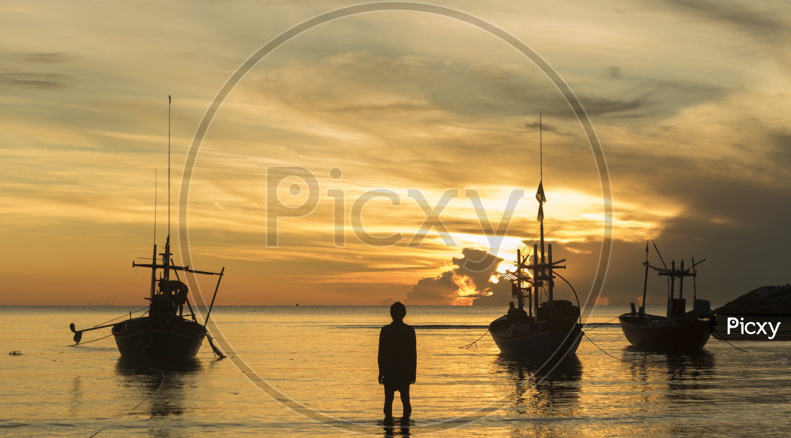 Fishing Boats In a Beach With  Fisherman Carrying Their Catch Over a Golden Sunset Sky In Background