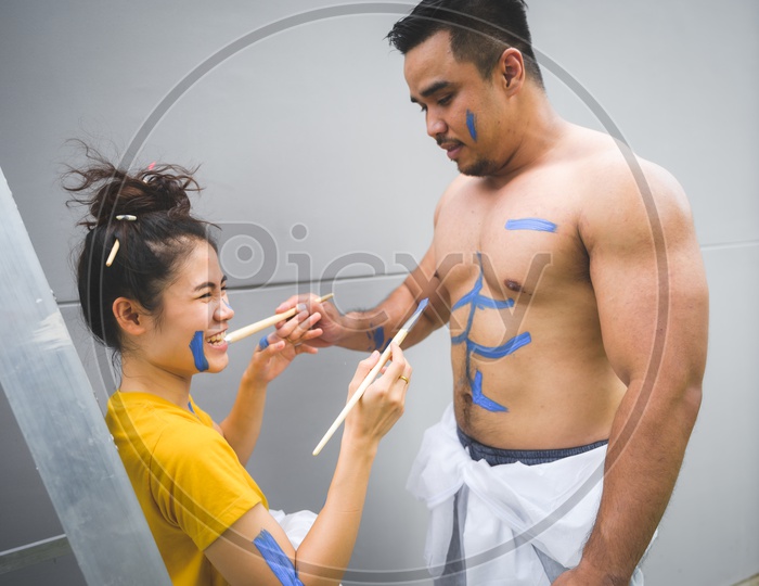 Affectionate Lovely Couple Celebrating love by Painting Their Bodies With Paint With brushes And Enjoying  in a House
