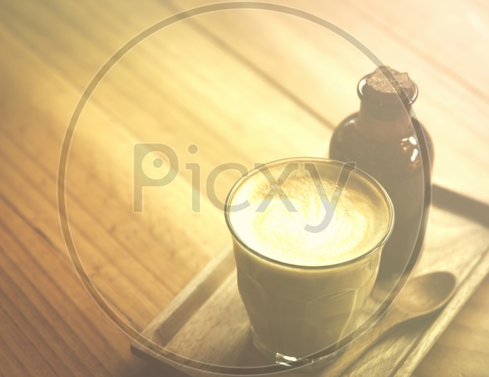 Coffee Latte Art On a Coffee With Sugar Syrup Bottle On Cafe Wooden table Background And with Vintage Filter