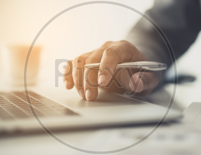 Businessman With Pen in Hand With Laptop and Office Desk Background
