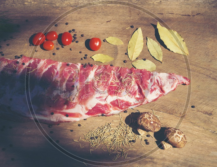 Raw ribs with a rosemary and vegetables on wooden chopping board