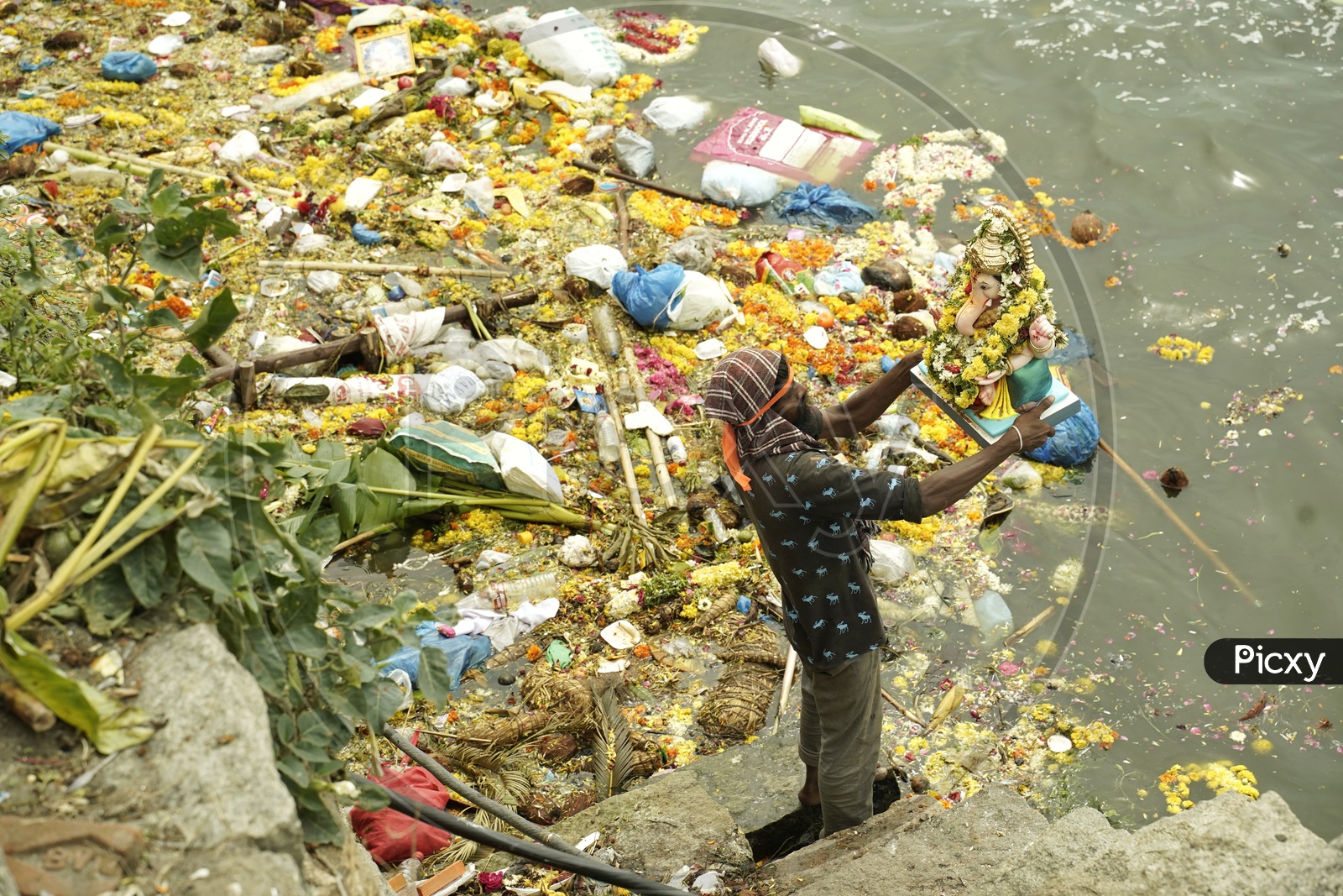 Man with the Ganesh idol on the day of Ganesh nimajjanam in a polluted lake. 