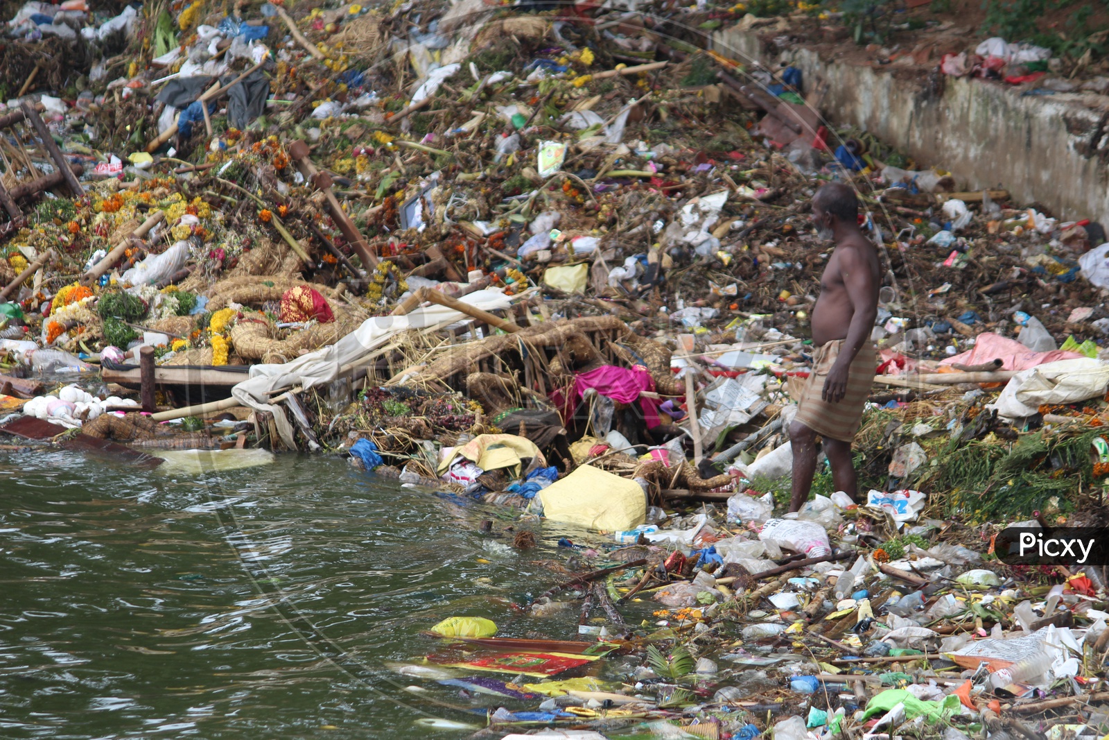 Man collecting the plastic in the tank bund on the day of Ganesh nimajjanam.