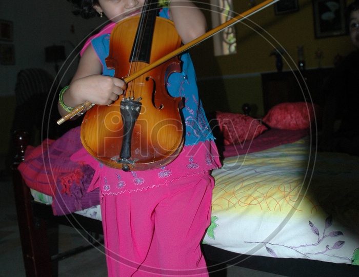 Indian little girl trying to play violin