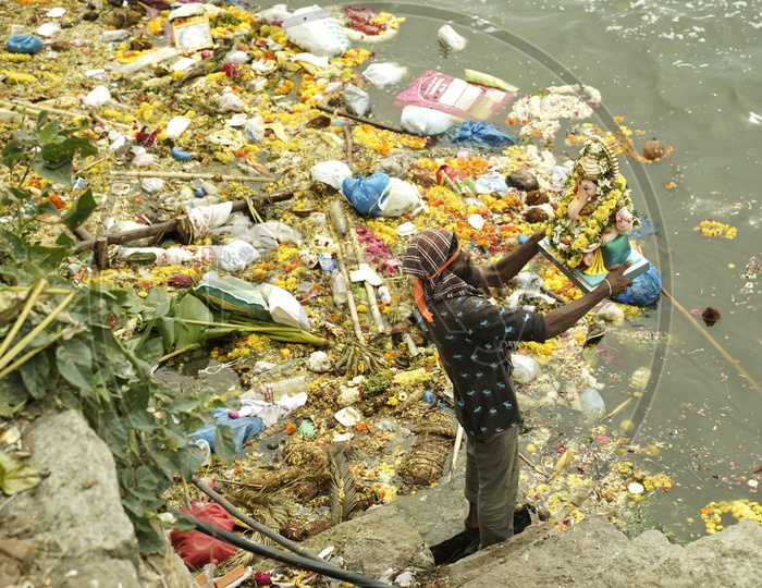 Man with the Ganesh idol on the day of Ganesh nimajjanam in a polluted lake. 