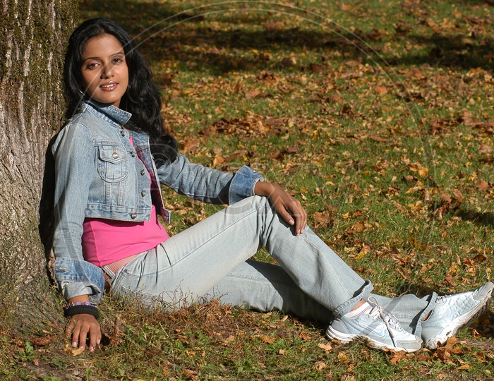 Indian girl sitting in a lawn with autumn leaves